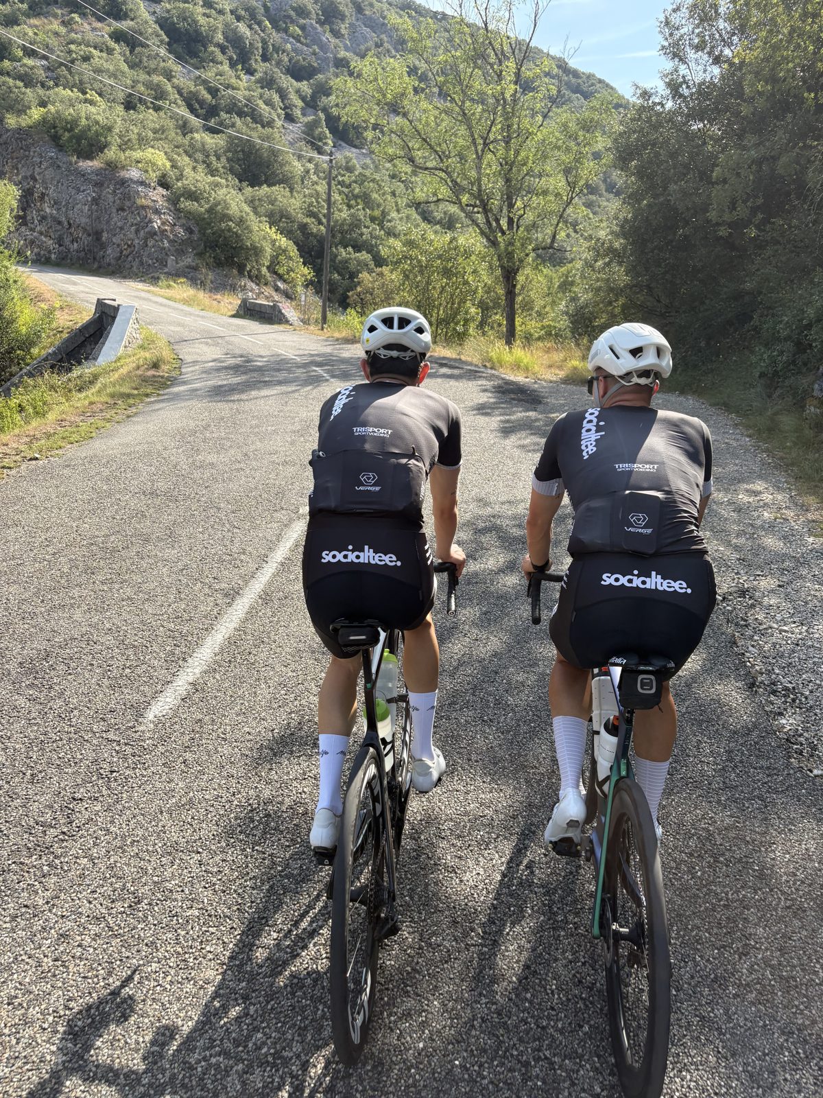 Community foto — wielrenners in Socialtee wielerkledij op een col