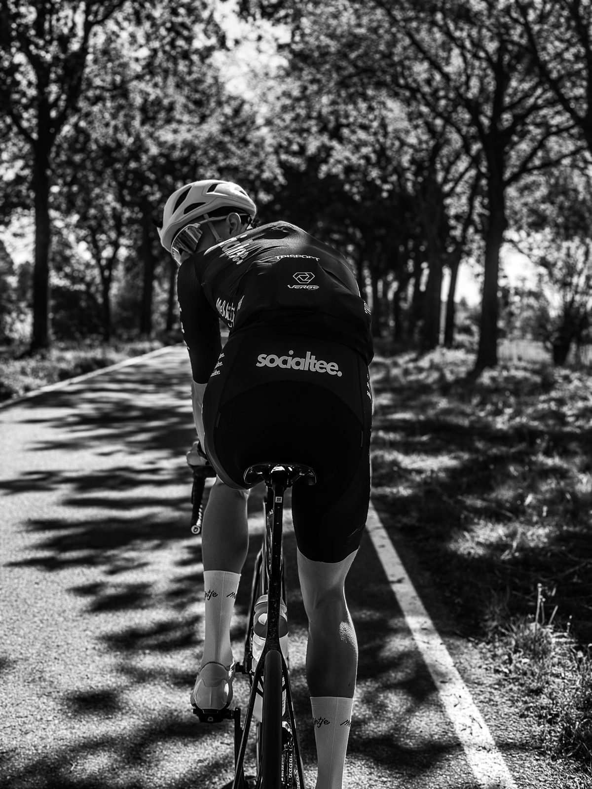 Community foto — wielrenner op een boomrijke fietsroute in Socialtee kledij