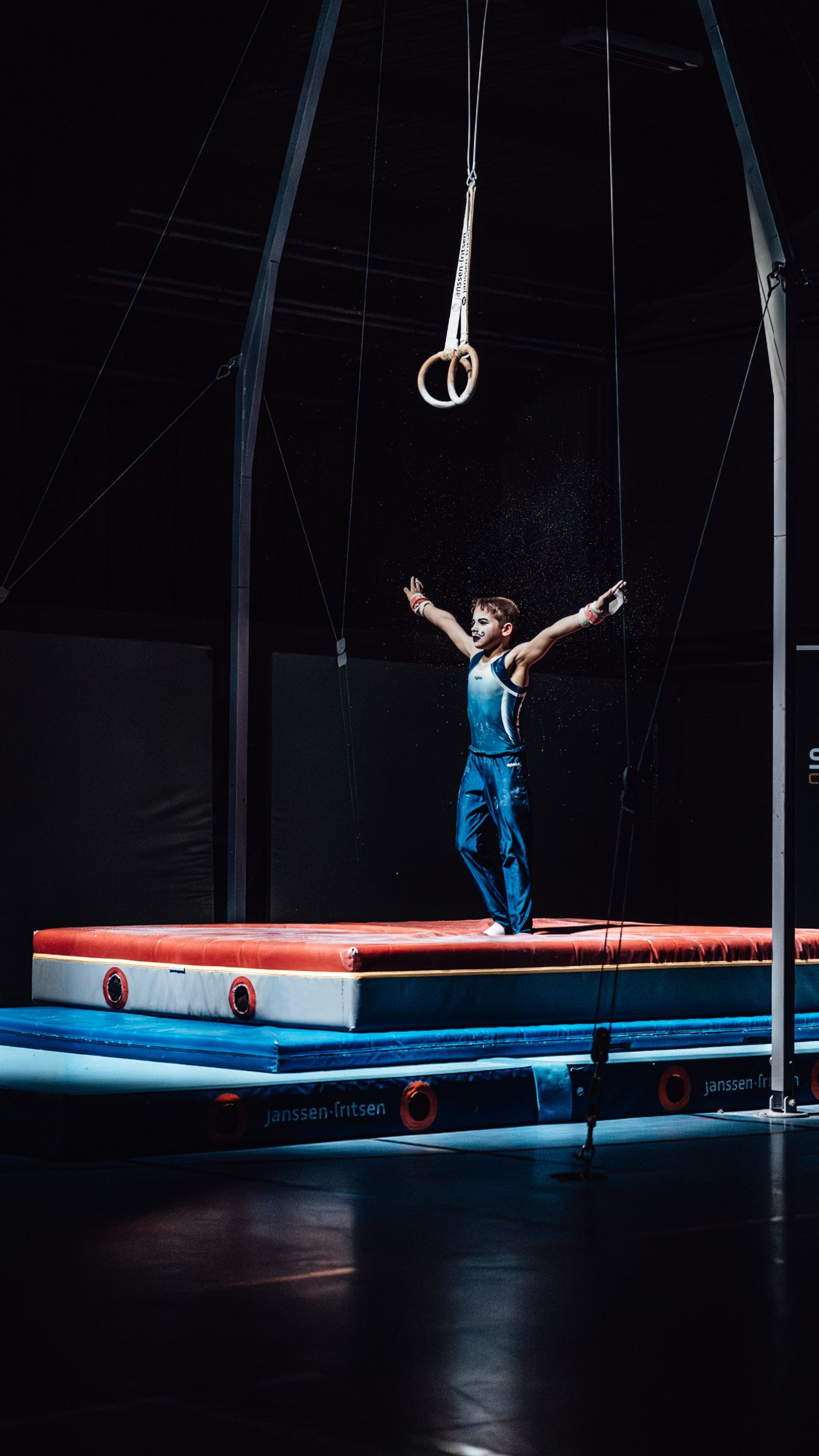 Jonge turner op de ringen tijdens gymnastics optreden