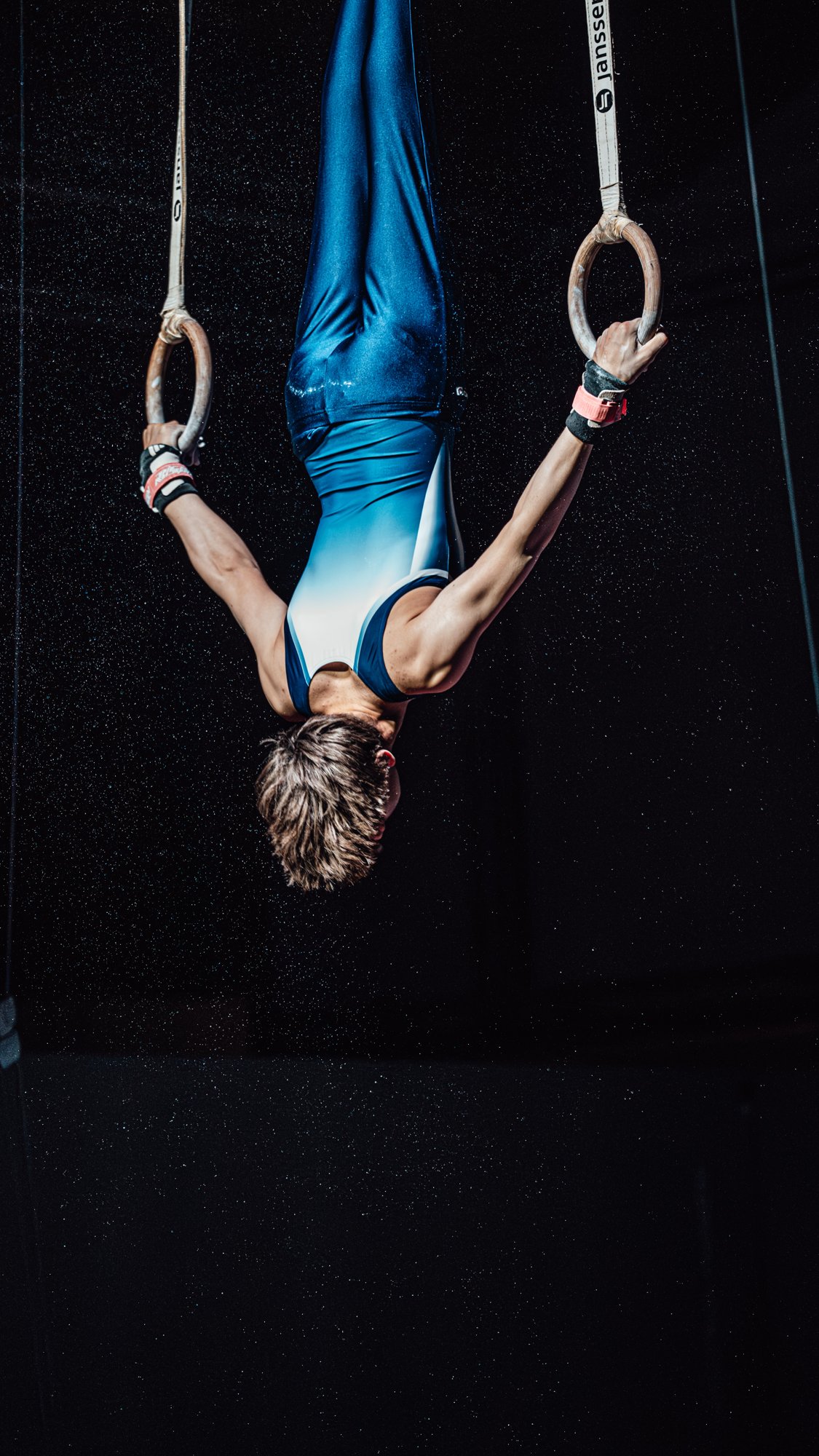 Turner ondersteboven aan de ringen tijdens gymnastics